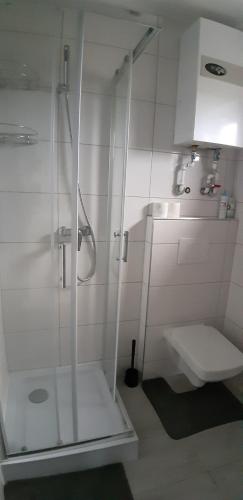 y baño blanco con ducha y aseo. en Przytulny domek en Darłówko