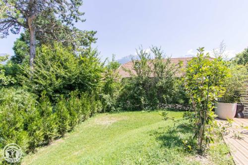 un jardin avec des arbres et des buissons dans une cour dans l'établissement L'appartement JARDIN avec vue montagnes, à Sévrier