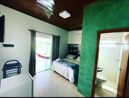 a bedroom with a bed and a bathroom with a toilet at Pousada Caminho das Cachoeiras Pirenopolis in Pirenópolis