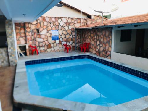 a swimming pool in front of a stone wall at Pousada Caminho das Cachoeiras Pirenopolis in Pirenópolis