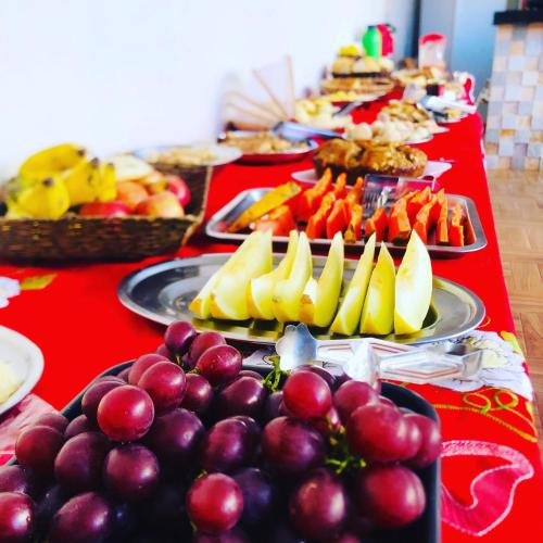 a red table topped with plates of fruits and vegetables at Pousada Caminho das Cachoeiras Pirenopolis in Pirenópolis
