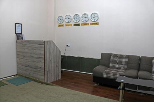 Habitación con sofá y relojes en la pared en Chinor Garden Hotel - Free Airport Pick-up and Drop-Off, en Tashkent