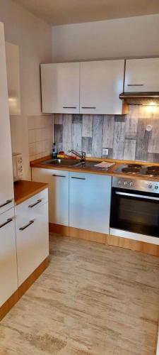 a kitchen with white cabinets and a black oven at Panoramic Apartments Hohegeiß in Hohegeiß