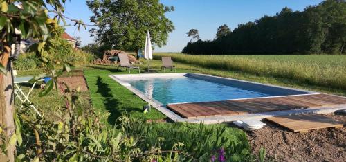 una piscina con terraza de madera junto a un campo en LES LIMORNIERES, en Le Grand-Pressigny