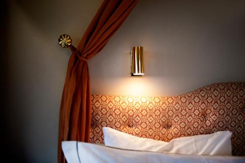 a bedroom with a bed with a curtain and a light at Åkerblads Hotell Gästgiveri Spa in Tällberg