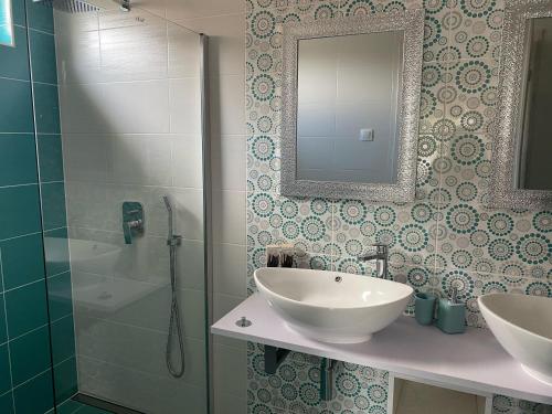 een badkamer met een wastafel, een douche en een spiegel bij BB Vendégház in Villány