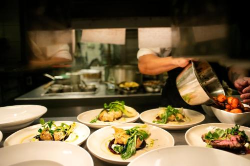 a chef preparing plates of food in a kitchen at Åkerblads Hotell Gästgiveri Spa in Tällberg