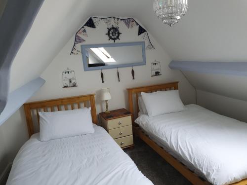 - 2 lits dans une chambre avec une horloge sur le mur dans l'établissement Chartwell Retreat, à Whitby