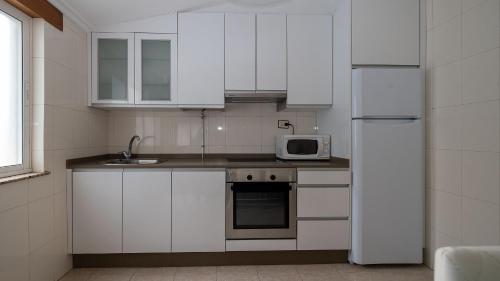 a kitchen with white cabinets and a white refrigerator at Apartamento Loli 4 in Viveiro