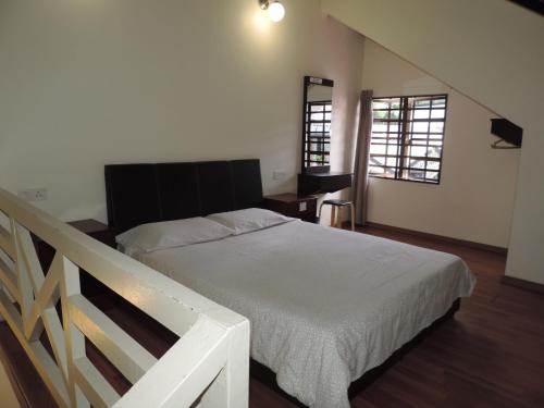a bedroom with a white bed and a staircase at Cameronian Inn in Cameron Highlands