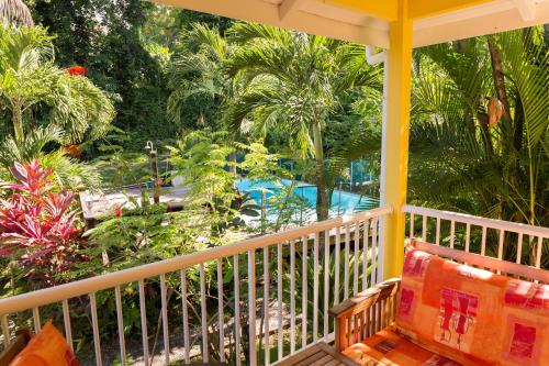 - une terrasse couverte avec un banc et une vue sur la piscine dans l'établissement Les Jardins de l'Espérance, à Bouillante