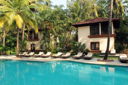 a resort swimming pool with lounge chairs and a house at Coconut Creek Resort - Dabolim Airport in Bogmalo