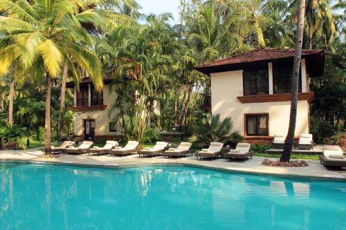 a resort swimming pool with lounge chairs and a house at Coconut Creek Resort - Dabolim Airport in Bogmolo