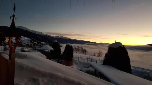 a view of a snow covered field with the sun setting in the background at Residence Condor Apt Schlern in Maranza