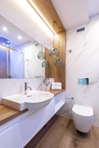 a white bathroom with a sink and a toilet at Tatra Resort & SPA in Kościelisko
