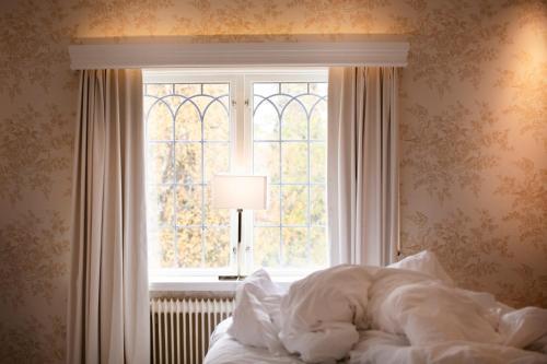 a bedroom with a bed and a window at Åkerblads Hotell Gästgiveri Spa in Tällberg