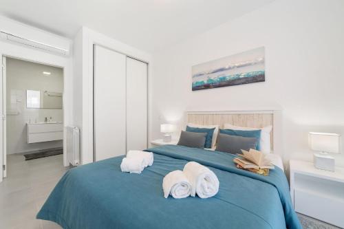 a bedroom with a blue bed with towels on it at Muralha 2 - Holiday Apartments - By SCH in Nazaré