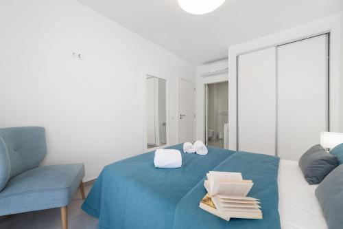 a bedroom with a blue bed with towels and a chair at Muralha 2 - Holiday Apartments - By SCH in Nazaré