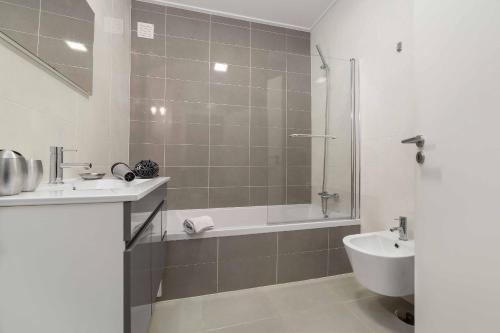 a bathroom with a shower and a tub and a sink at Casas do Parque - By SCH in São Martinho do Porto