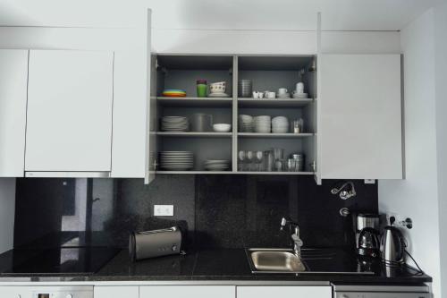 a kitchen with white cabinets and a sink and a counter at Deluxe Villa - By SCH in Salir de Porto