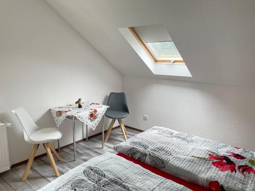 a bedroom with a bed and a table and a skylight at FeWo mit Balkon direkt am Wald und Wanderweg Ruhe pur 2 OG in Bad Sachsa