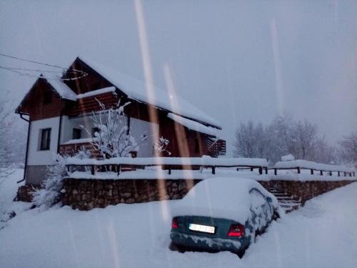 a car covered in snow in front of a house at Studio Apartmani Patricia in Smoljanac