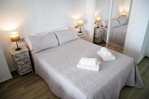 sypialnia z białym łóżkiem i 2 ręcznikami w obiekcie Neenies Nerja - Carabeo Luxury Apartment w mieście Nerja