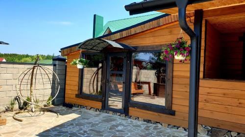 a wooden house with a glass door on a patio at Садиба For Rest in Svityazʼ