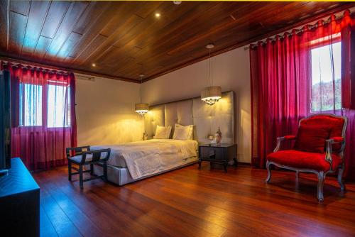 a bedroom with a bed and a red chair at Valonquinta - Agro Hotel & SPA in Vila Flor