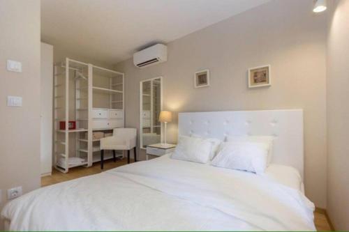 a white bedroom with a white bed and a desk at Sea view House Fontera in Rovinj