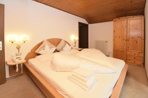 a bedroom with a large white bed with a wooden headboard at Hotel Chalet Olympia in Monguelfo