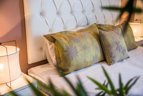 a bed with two pillows on it with two lamps at Aqua Mare Hotel in Nea Kalikratia