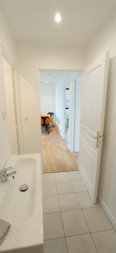 une salle de bain avec un lavabo et une pièce avec une table dans l'établissement Appart Coeur de Rouen - Majestic, à Rouen