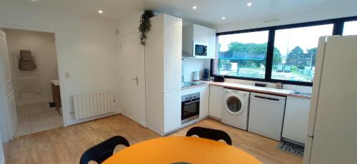Il comprend une cuisine avec une table et un lave-linge. dans l'établissement Appart Coeur de Rouen - Majestic, à Rouen