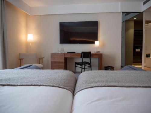a hotel room with two beds and a flat screen tv at Hotel Palacio La Marquesa 4 Estrellas SUP in Teruel