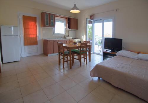 a bedroom with a bed and a table and a kitchen at Kostas & Eleni Apartments in Sotirítsa