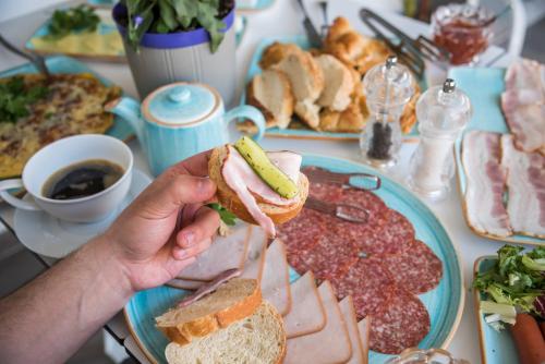 a person holding a sandwich on a table with meats at Aqua Mare Hotel in Nea Kalikratia