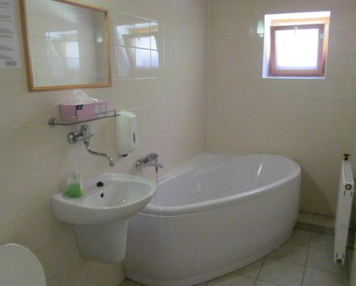 a white bath tub and a sink in a bathroom at A+S Penzion Podzamok in Spišské Podhradie