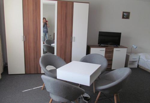 a woman taking a picture of a room with chairs and a table at A+S Penzion Podzamok in Spišské Podhradie