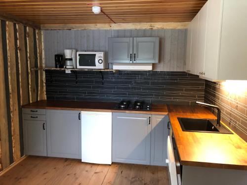 a small kitchen with white cabinets and a microwave at Storbo Adventure Camp in Storbo