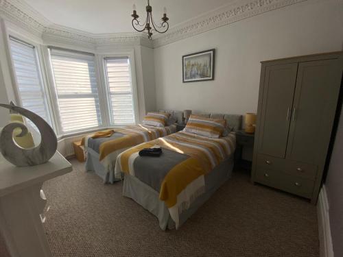 a bedroom with three beds and a chandelier at Penhale Holiday Flats in Eastbourne