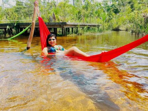 Ein Mädchen, das auf einer Hängematte im Wasser sitzt in der Unterkunft Rancho Lisboa Cocal in Queimada
