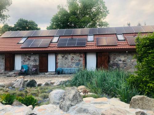 Siedlisko Żywe Kamienie في Naguszewo: منزل على السطح مع لوحات شمسية