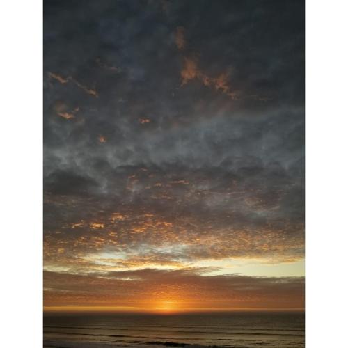 a sunset over the ocean with clouds at Mar del Este in San Bernardo