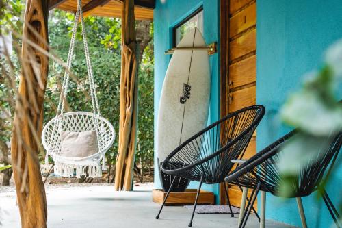 a porch with a swing and a surfboard on a house at SoulShine in Playa Avellana