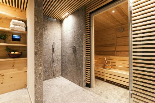 a walk in shower in a bathroom with wooden walls at Chalet Marmotta NEVE - Luxus Chalet in Sankt Anton am Arlberg