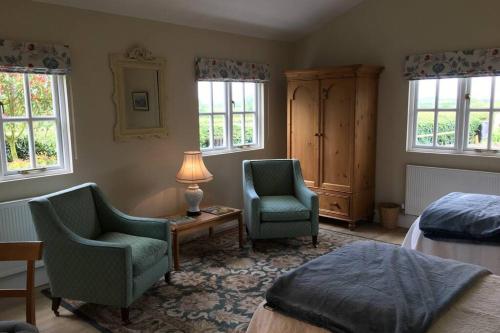 a bedroom with two chairs and a bed and a lamp at Private Annex near Melton Mowbray in Melton Mowbray