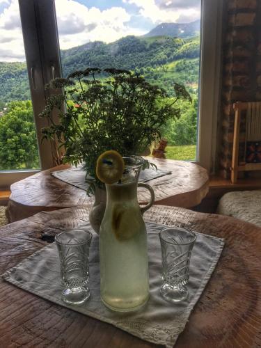 a vase with a plant and two glasses on a table at Konak Umoljani in Umoljani