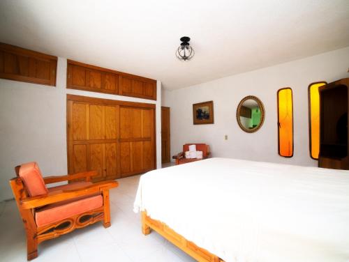 um quarto com uma cama, uma cadeira e um espelho em Casa de las Cruces Taxco em Taxco de Alarcón