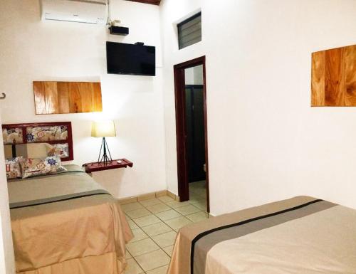 a room with two beds and a tv on the wall at Hostal Las Puertas in Santa Ana